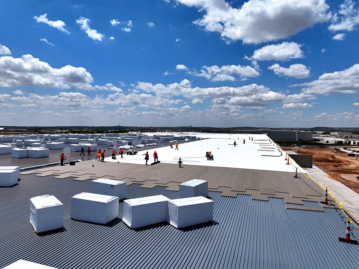 Crew staging insulation boards on a large warehouse's metal roof deck – TPO roofs project gallery