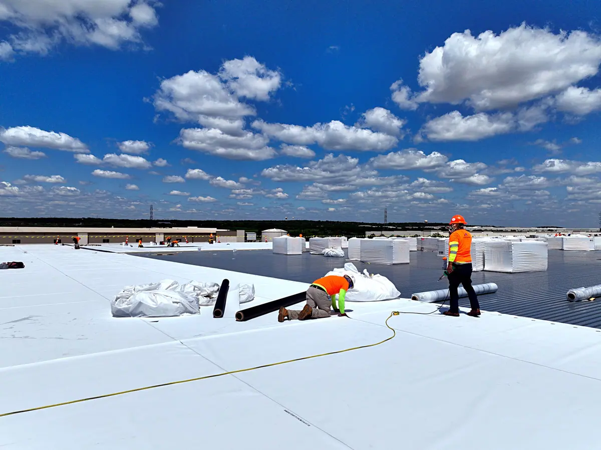 Crew installing a white TPO roof on a large warehouse – TPO roofs project gallery