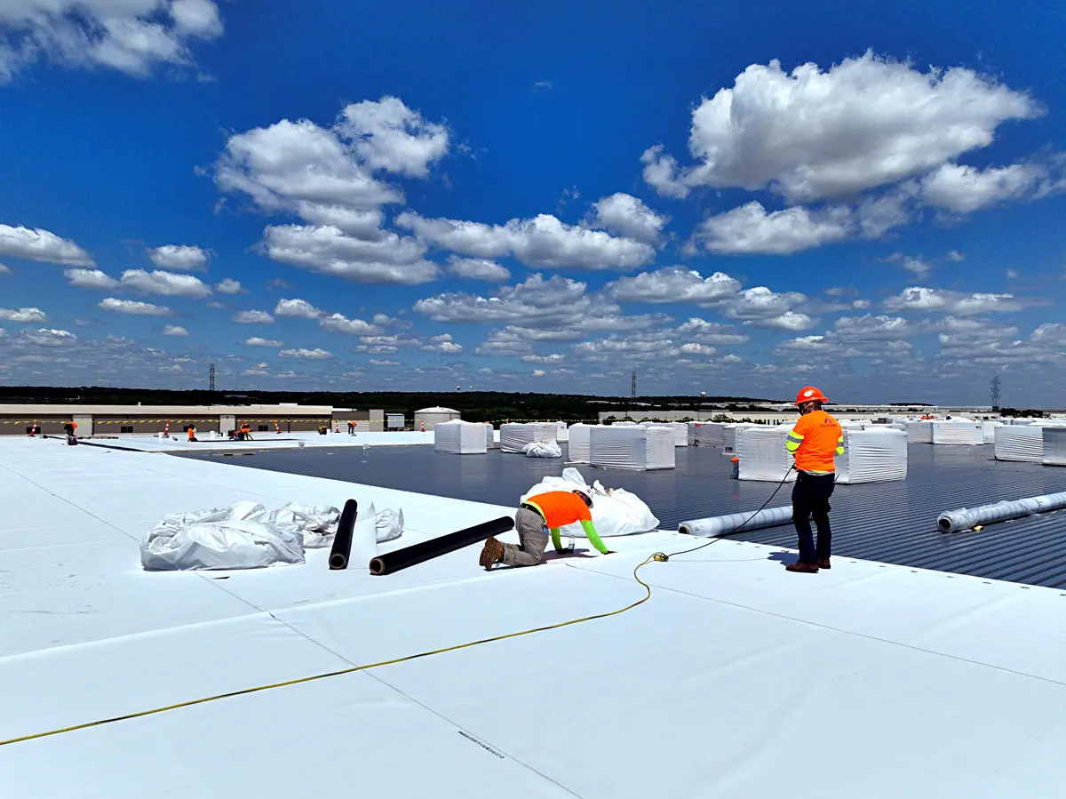 Crew installing a white TPO roof on a large warehouse – TPO roofs project gallery