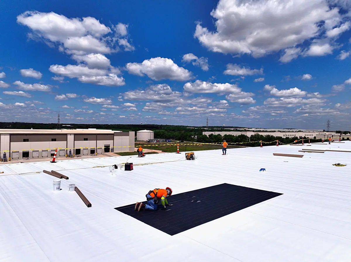Roofer working on a large white TPO warehouse roof – TPO roofs project gallery