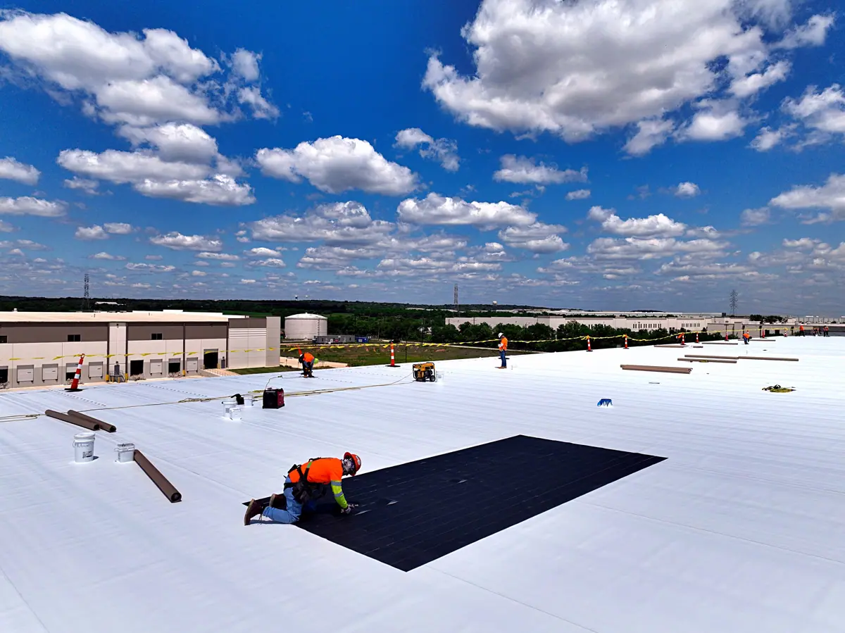 Roofer working on a large white TPO warehouse roof – TPO roofs project gallery