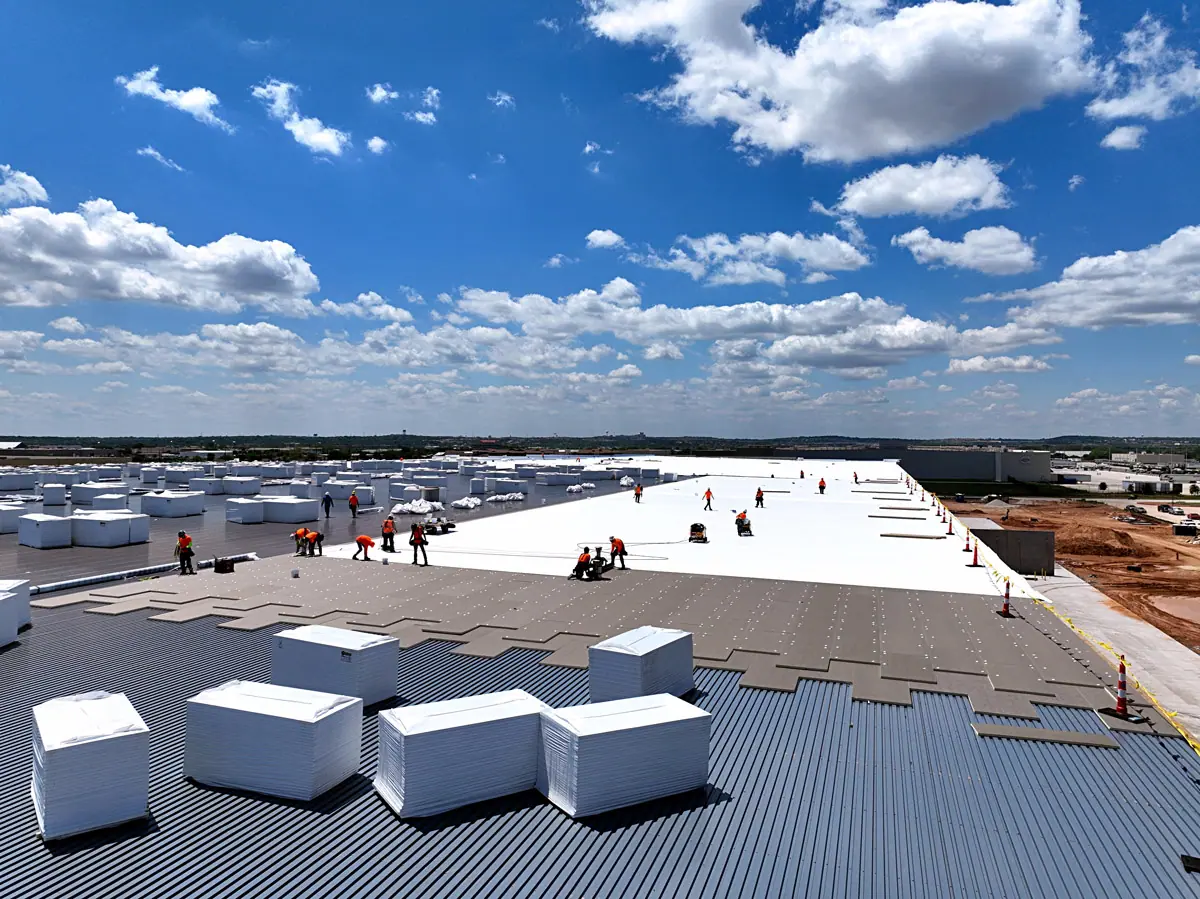 Crew staging insulation boards on a large warehouse's metal roof deck – TPO roofs project gallery