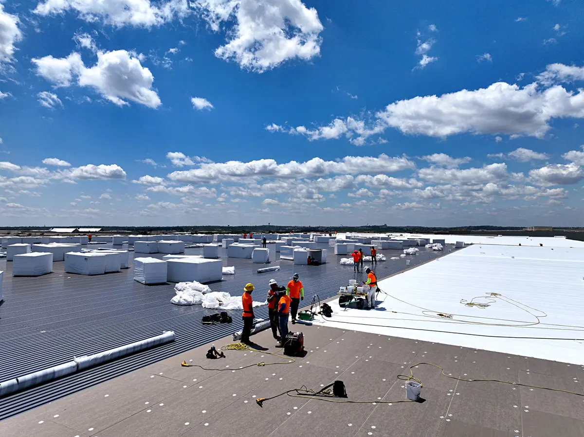 Crew installing a white TPO roof on a large warehouse – TPO roofs project gallery