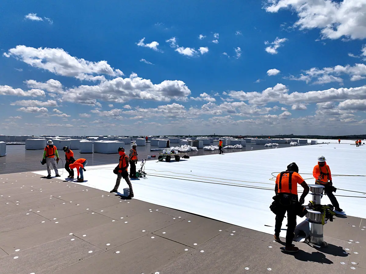 Crew installing a white TPO roof on a large warehouse – TPO roofs project gallery