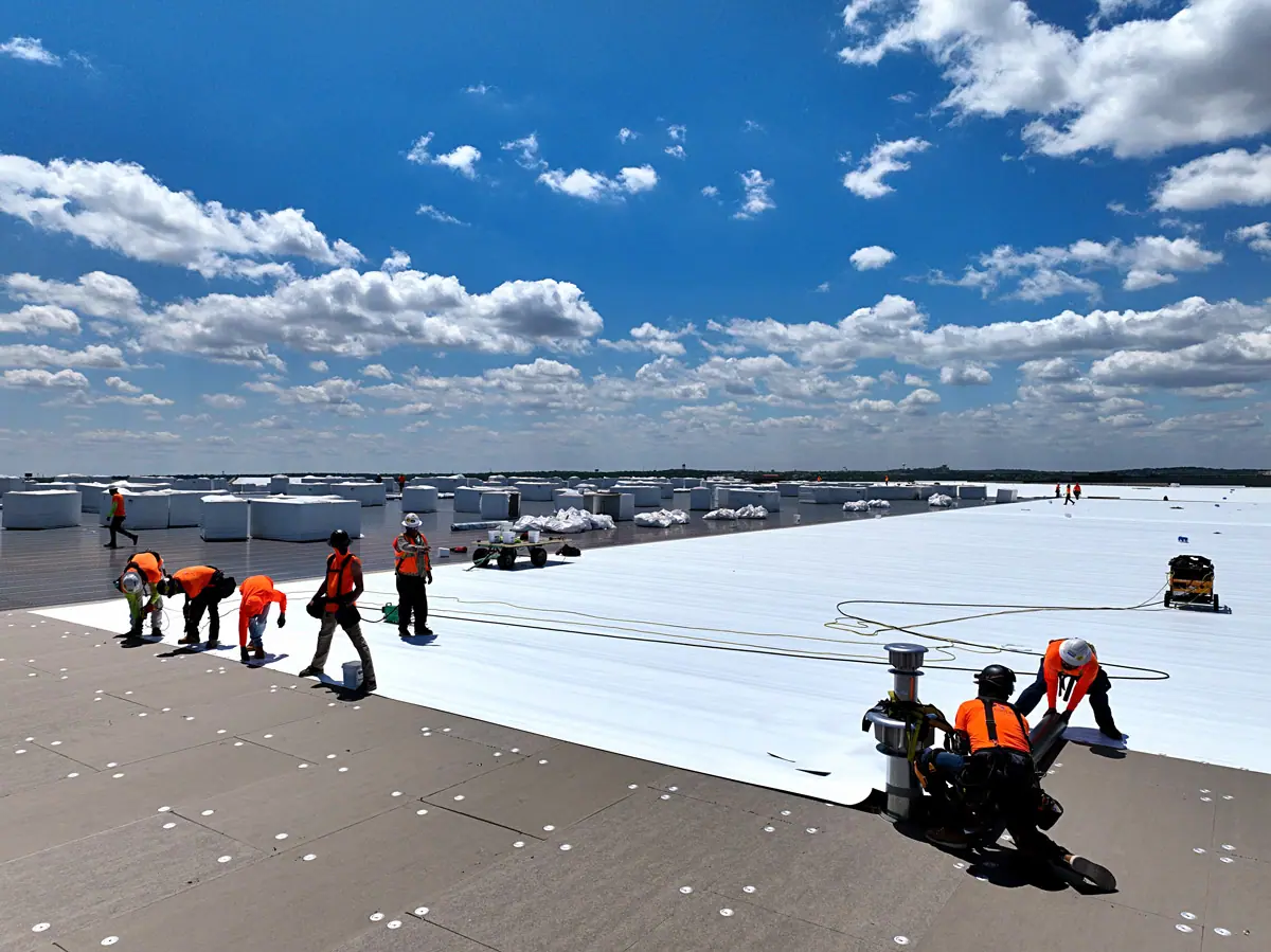 Crew installing a white TPO roof on a large warehouse – TPO roofs project gallery