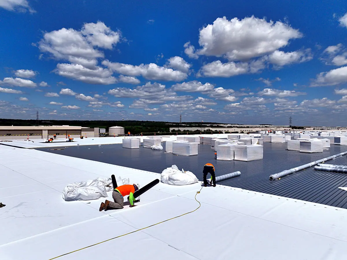 Crew installing a white TPO roof on a large warehouse – TPO roofs project gallery