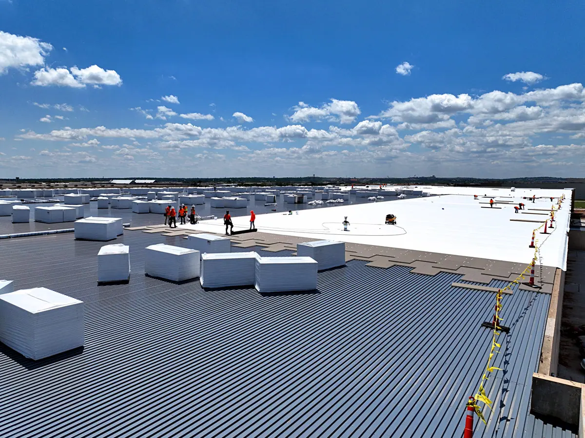 Crew staging insulation boards on a large warehouse's metal roof deck – TPO roofs project gallery