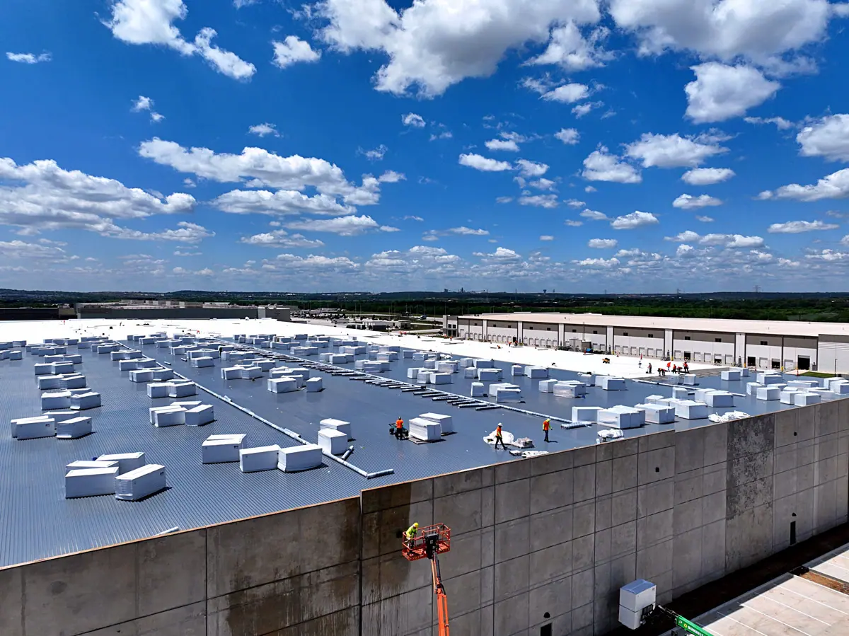 Lift raising roofing materials up a warehouse's concrete wall – TPO roofs project gallery