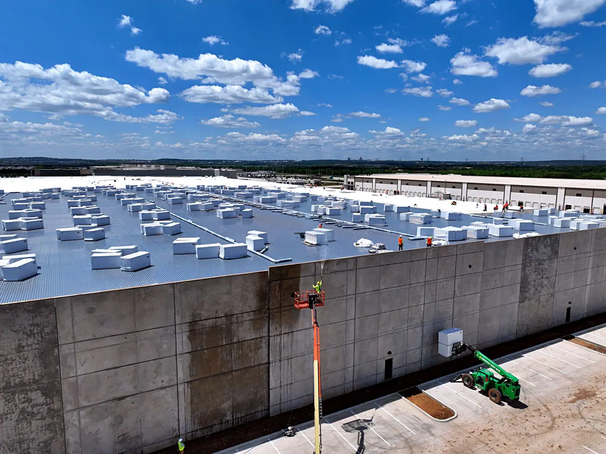 Lift raising roofing materials up a warehouse's concrete wall – TPO roofs project gallery