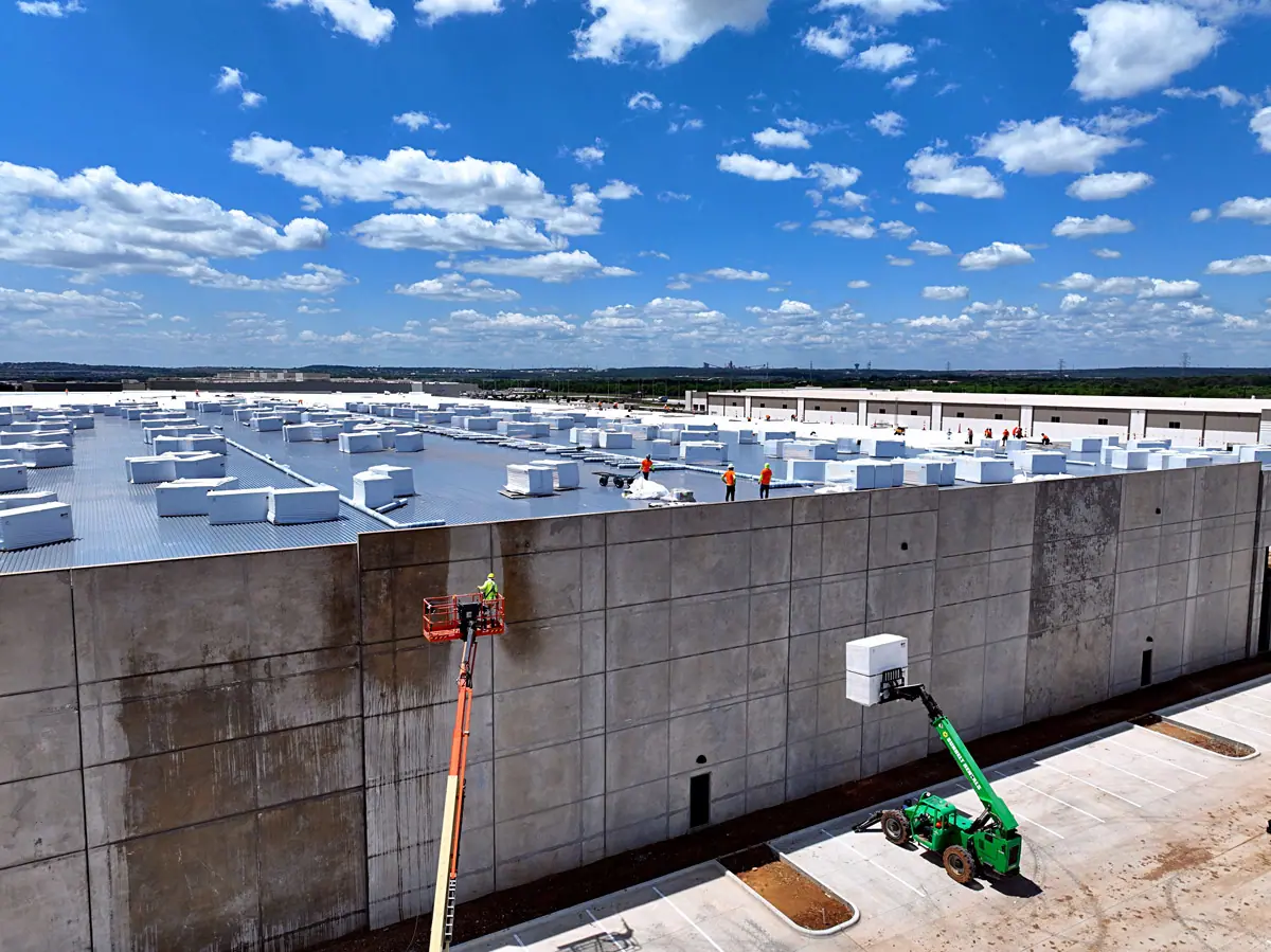 Lift raising roofing materials up a warehouse's concrete wall – TPO roofs project gallery
