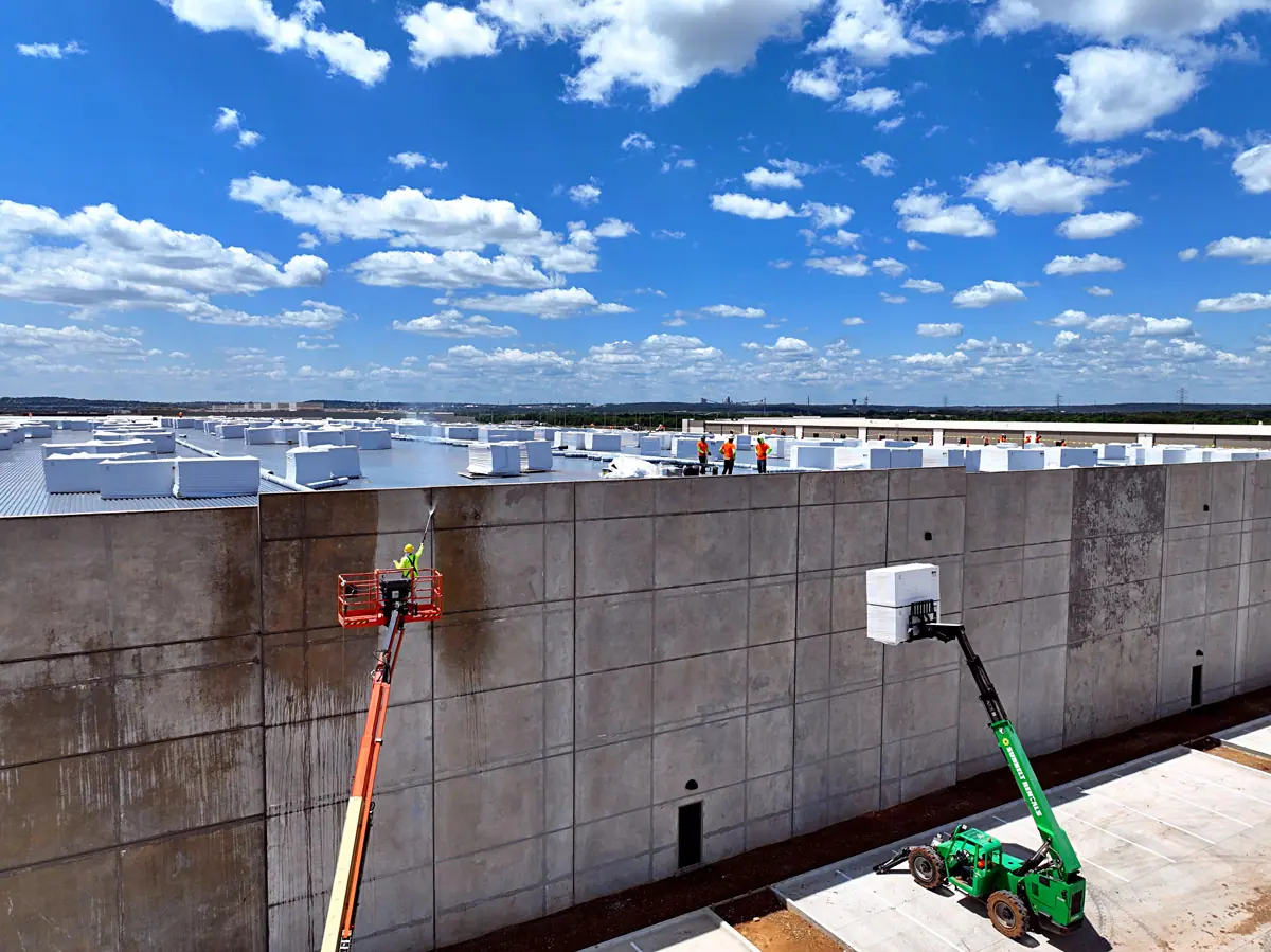 Lift raising roofing materials up a warehouse's concrete wall – TPO roofs project gallery