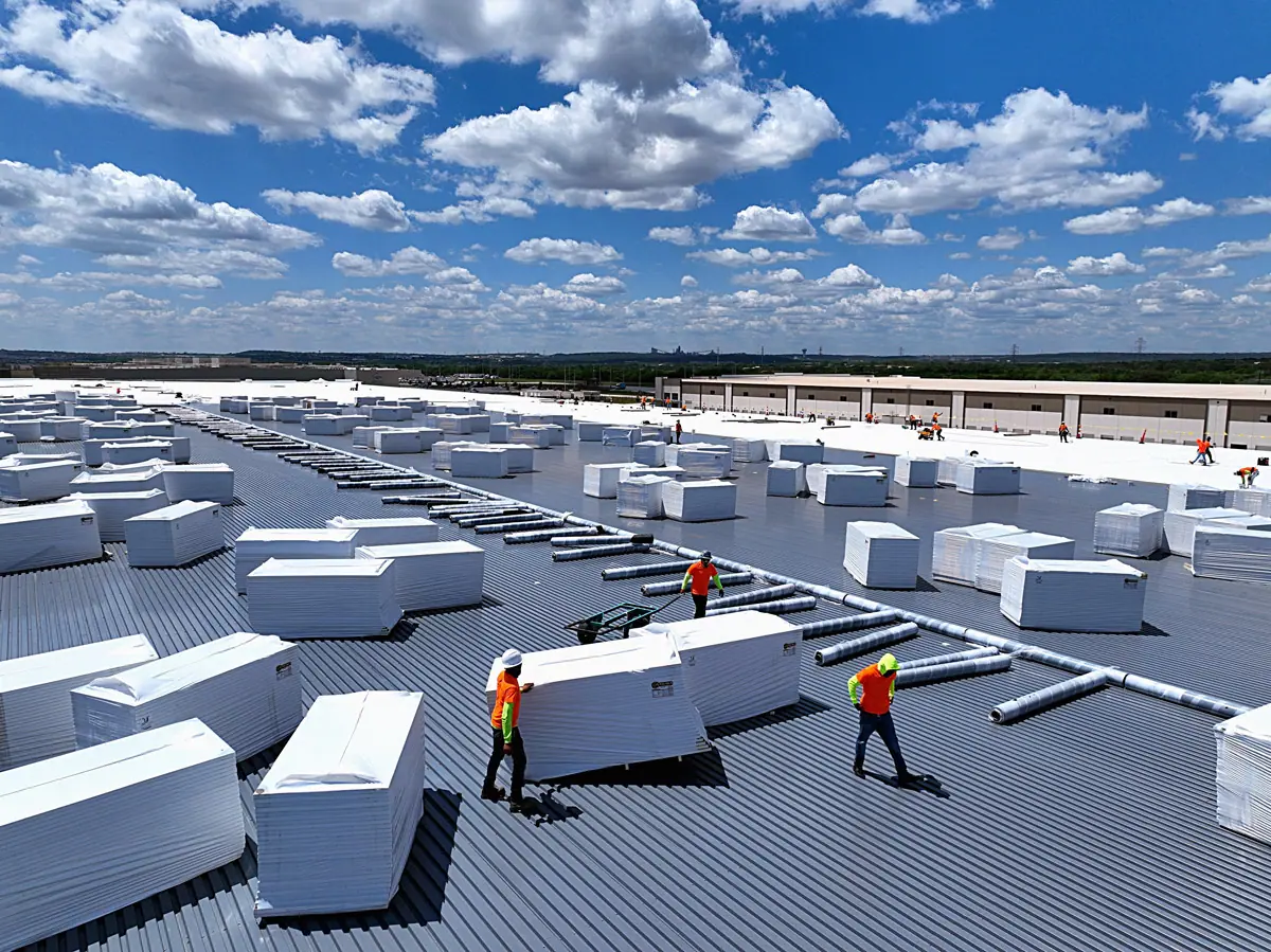 Crew staging insulation boards on a large warehouse's metal roof deck – TPO roofs project gallery