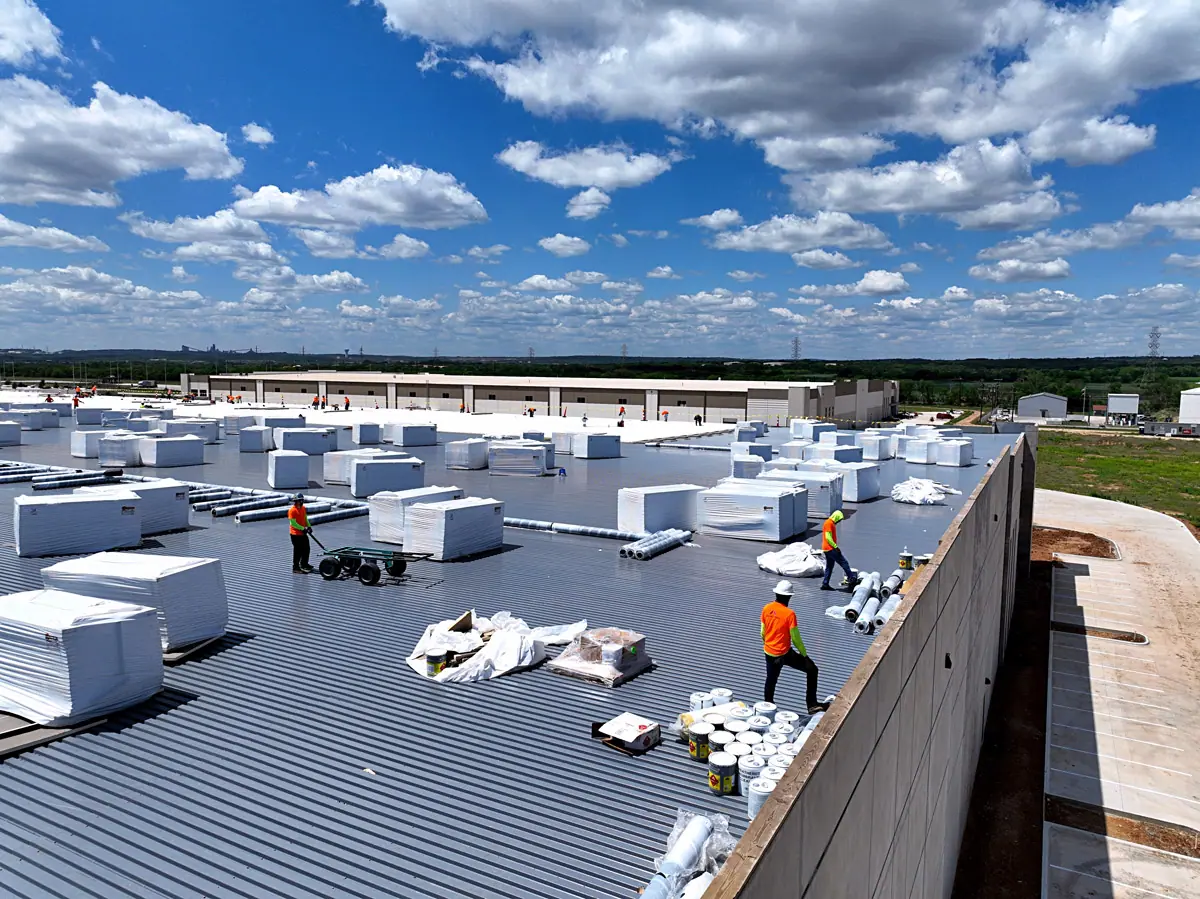 Crew staging insulation boards on a large warehouse's metal roof deck – TPO roofs project gallery