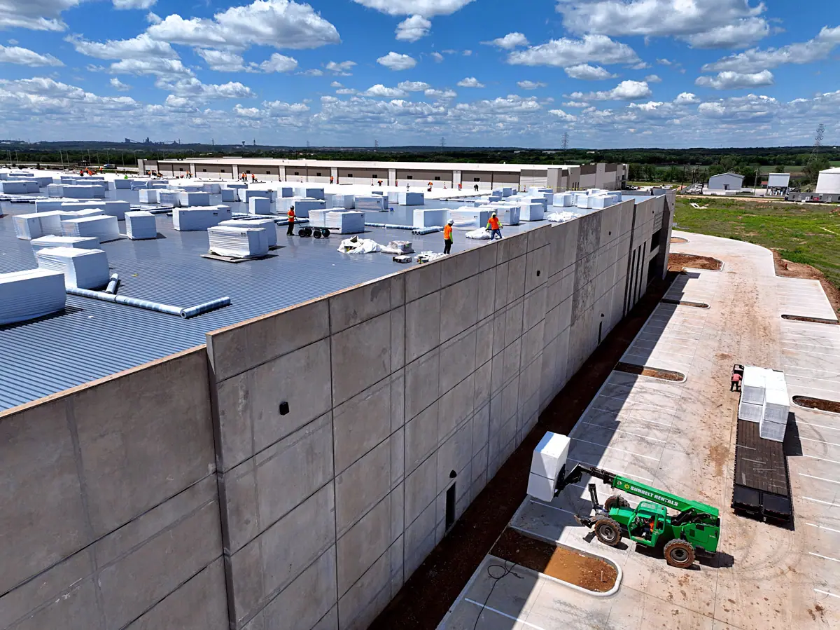 Lift raising roofing materials up a warehouse's concrete wall – TPO roofs project gallery