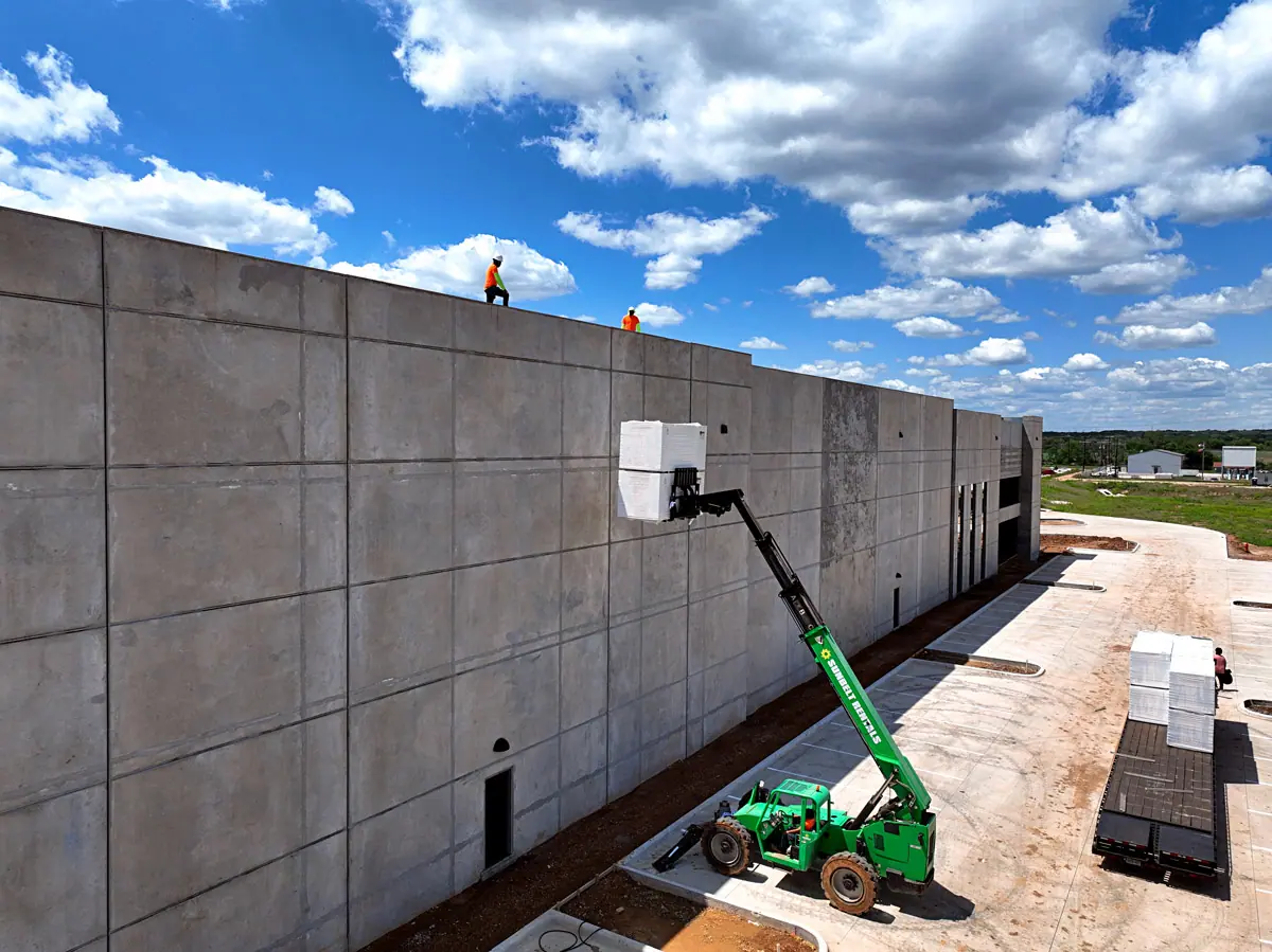 Lift raising roofing materials up a warehouse's concrete wall – TPO roofs project gallery