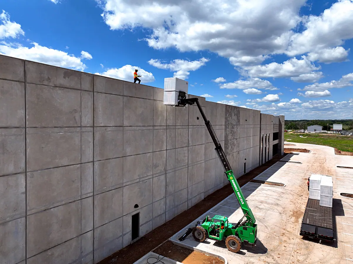 Lift raising roofing materials up a warehouse's concrete wall – TPO roofs project gallery