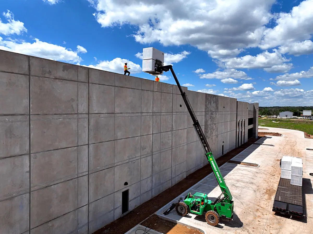 Lift raising roofing materials up a warehouse's concrete wall – TPO roofs project gallery