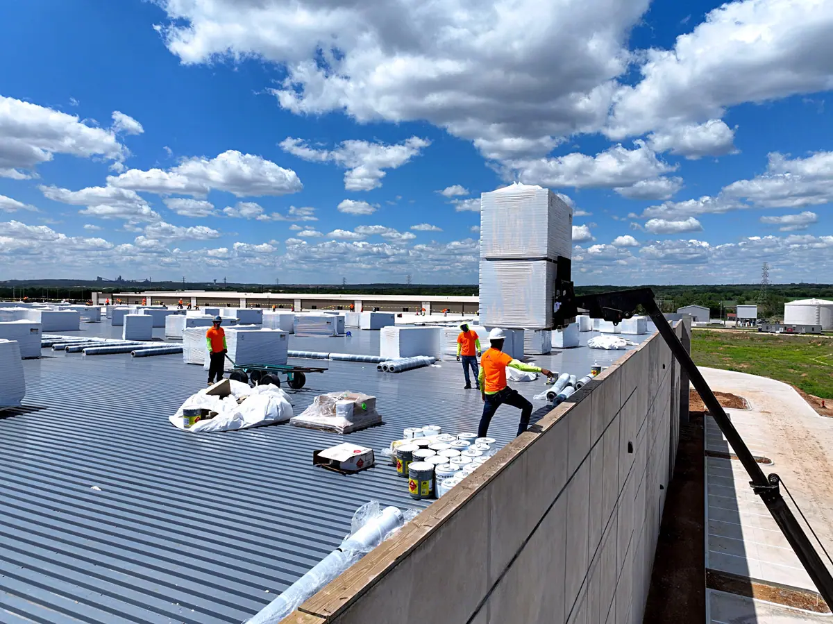 Crew unloading roofing materials onto a warehouse roof deck – TPO roofs project gallery