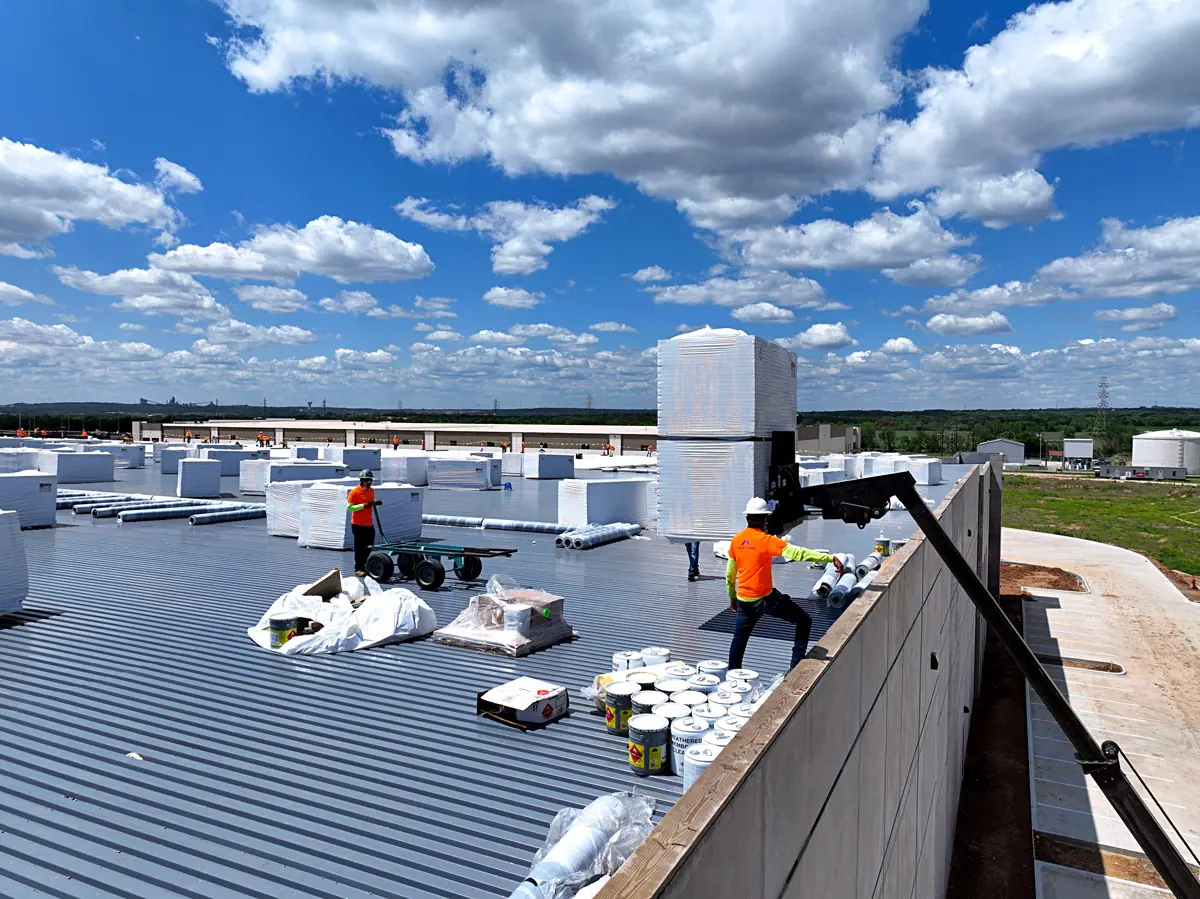 Crew unloading roofing materials onto a warehouse roof deck – TPO roofs project gallery