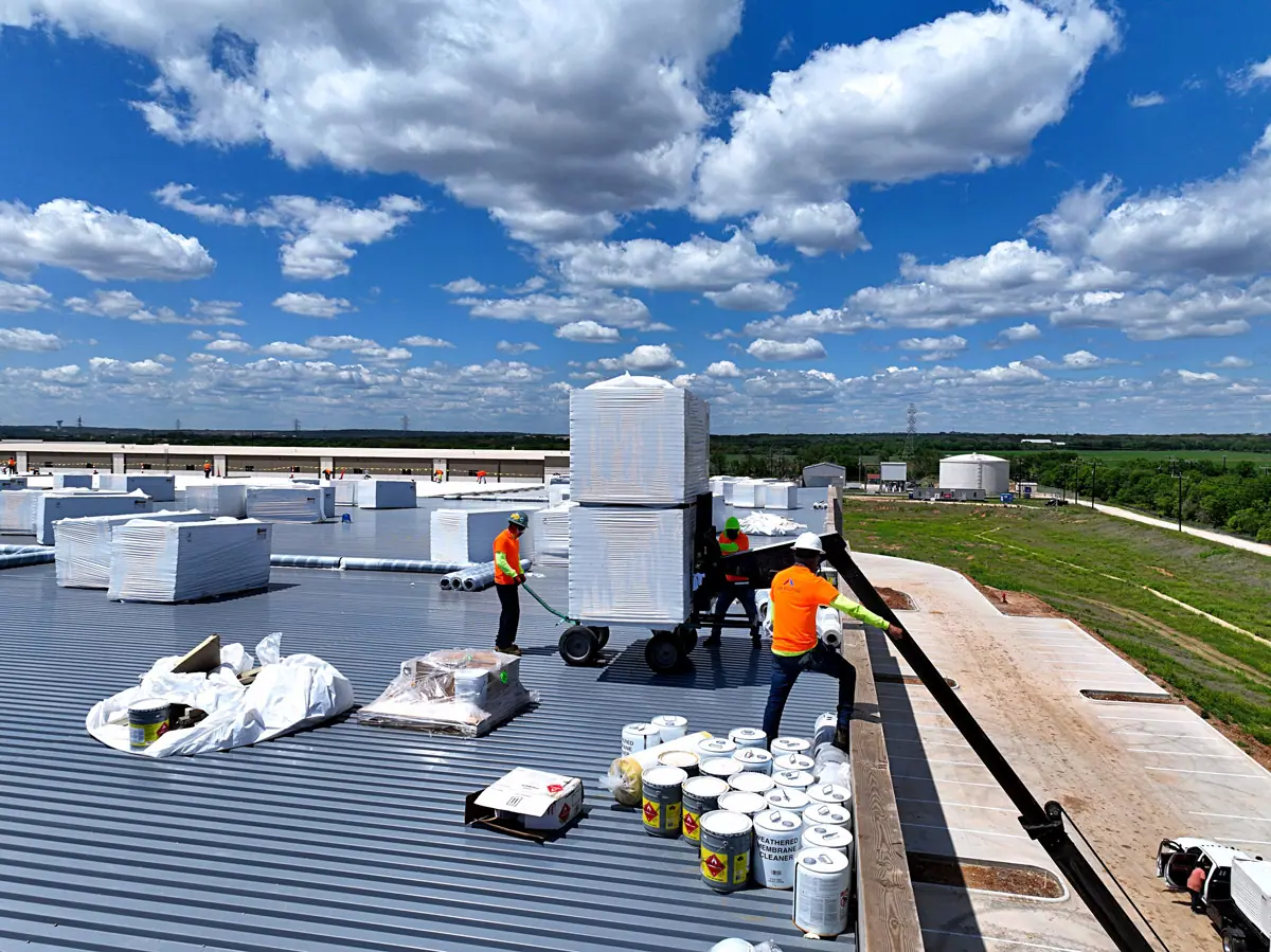 Crew unloading roofing materials onto a warehouse roof deck – TPO roofs project gallery