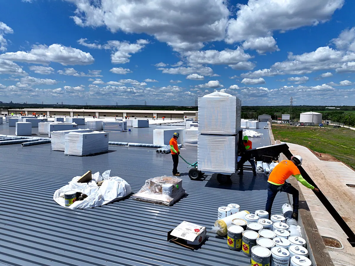 Crew unloading roofing materials onto a warehouse roof deck – TPO roofs project gallery