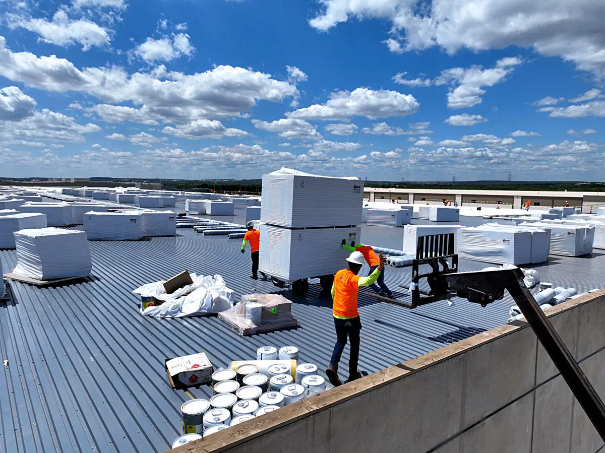 Crew unloading roofing materials onto a warehouse roof deck – TPO roofs project gallery