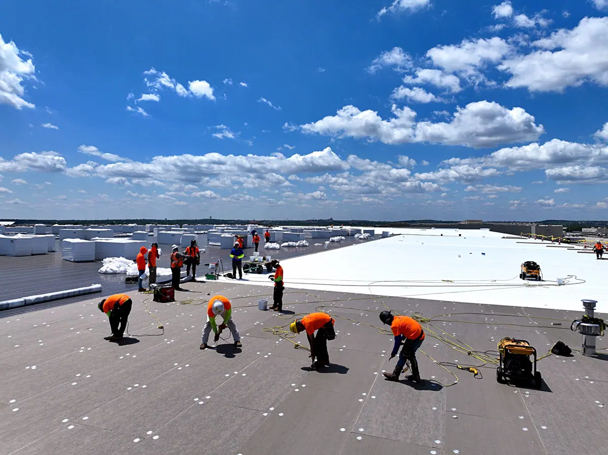 Crew installing a white TPO roof on a large warehouse – TPO roofs project gallery