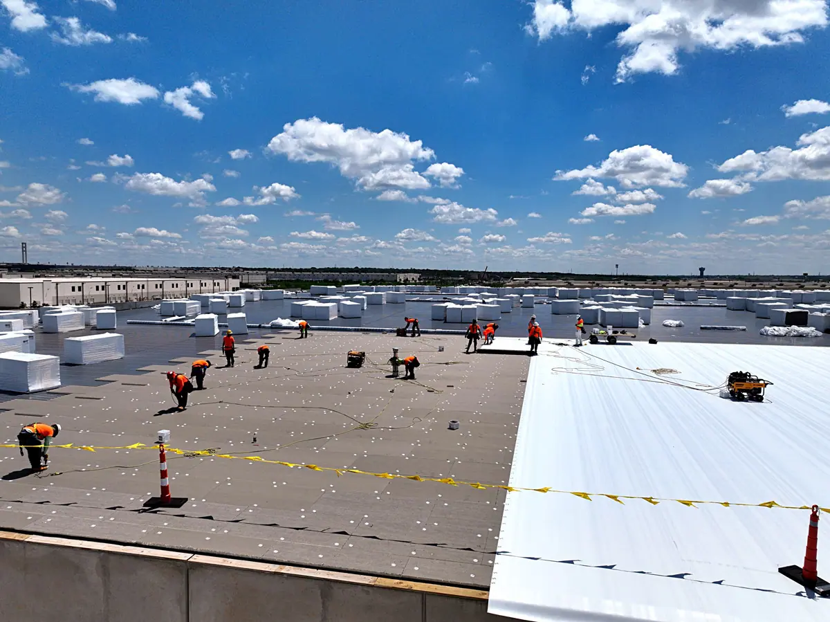 Crew installing a white TPO roof on a large warehouse – TPO roofs project gallery