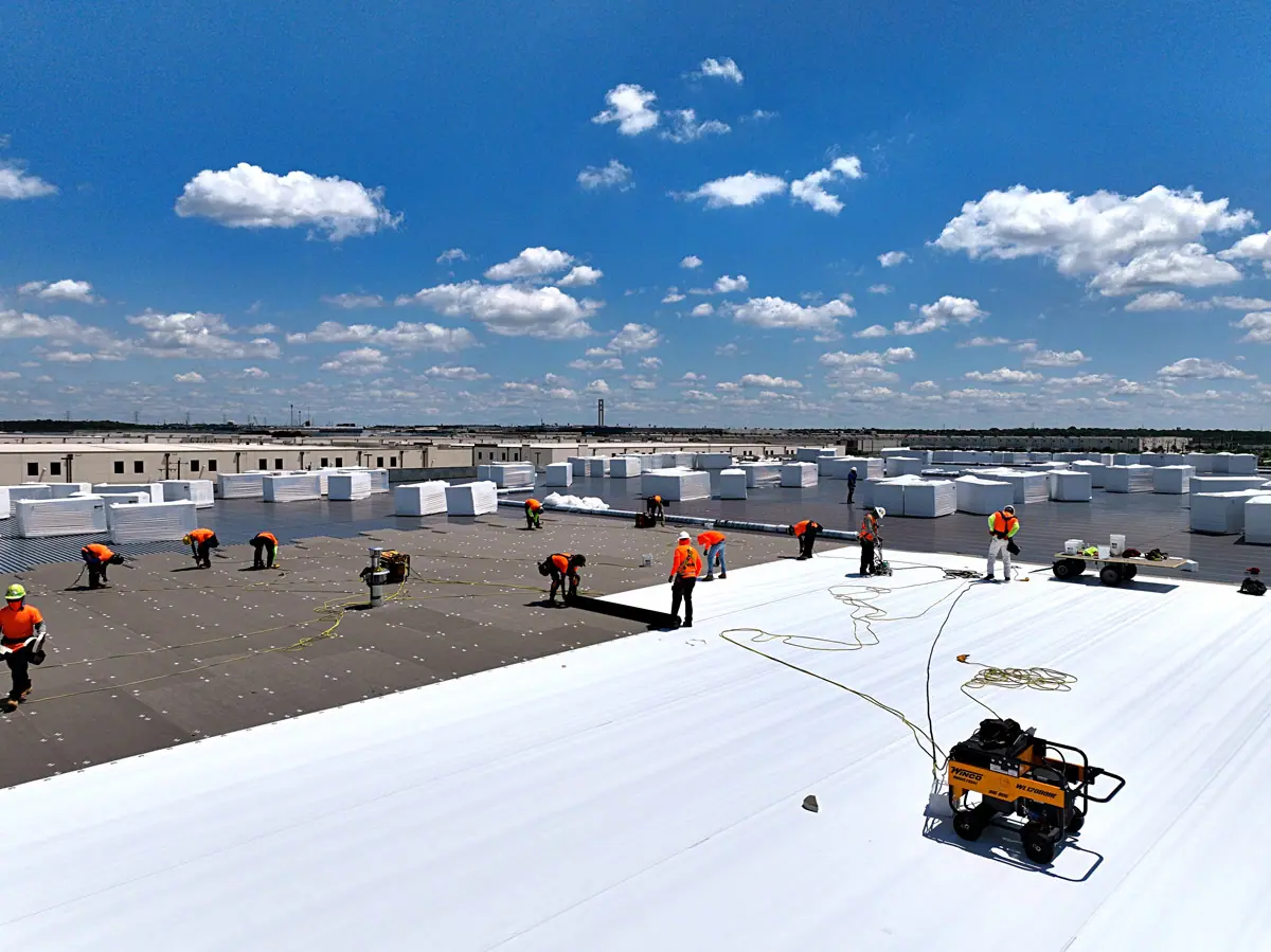 Crew installing a white TPO roof on a large warehouse – TPO roofs project gallery