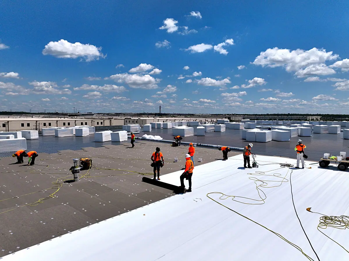 Crew installing a white TPO roof on a large warehouse – TPO roofs project gallery