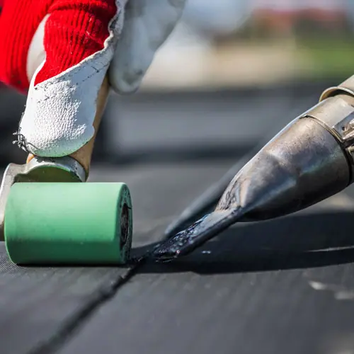 Roofer heat-welding a seam on a single-ply roof membrane – Waco roofing company